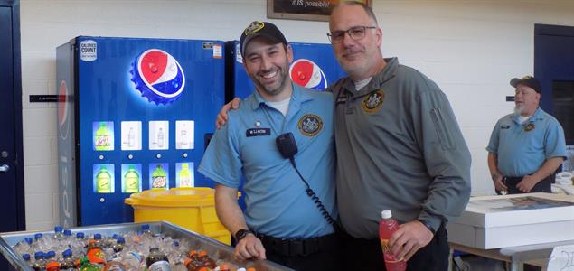 Two DOC employees stand with each other while getting bottled soda at the 10th anniversary party for SCI Houtzdale