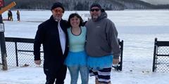 Three people stand in front of a frozen lake