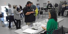 SCI Huntingdon Supt. John Rivello looks through his paperwork as a parole employee sits at a table during a reentry simulation