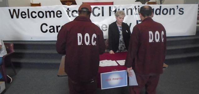 Two inmates meet with an attendee at the SCI Huntingdon reentry fair