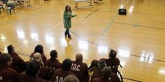 A woman speaks to an audience of inmates