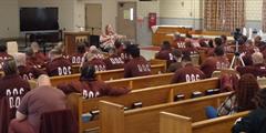 Inmates in a chapel watch a guest speaker