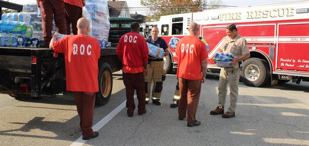 Workers of the SCI Laurel Highlands Community Work Program pass out packages of water bottles to firefighters