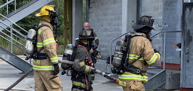 Three firefighters enter a building at a training simulation