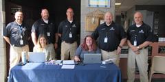 DOC employees stand and sit at a table in the SCI Mahanoy lobby for a job fair