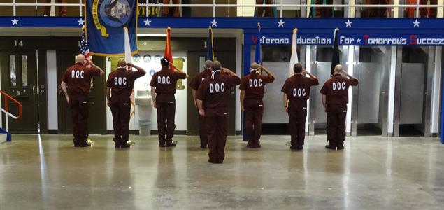 The inmate color guard salutes the flags