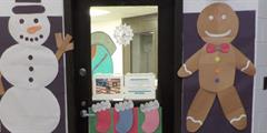 A doorway decorated with construction a paper snowman and gingerbread man
