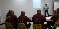 Five inmates watch a person present about the Veterans Treatment Court