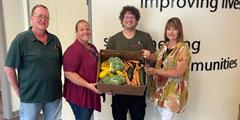 Four people holding a box of vegetables