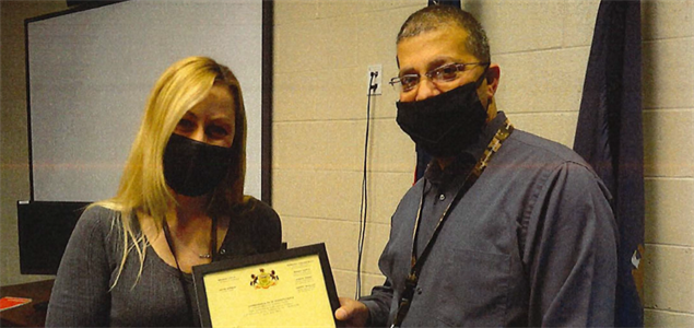 Two people stand with a certificate
