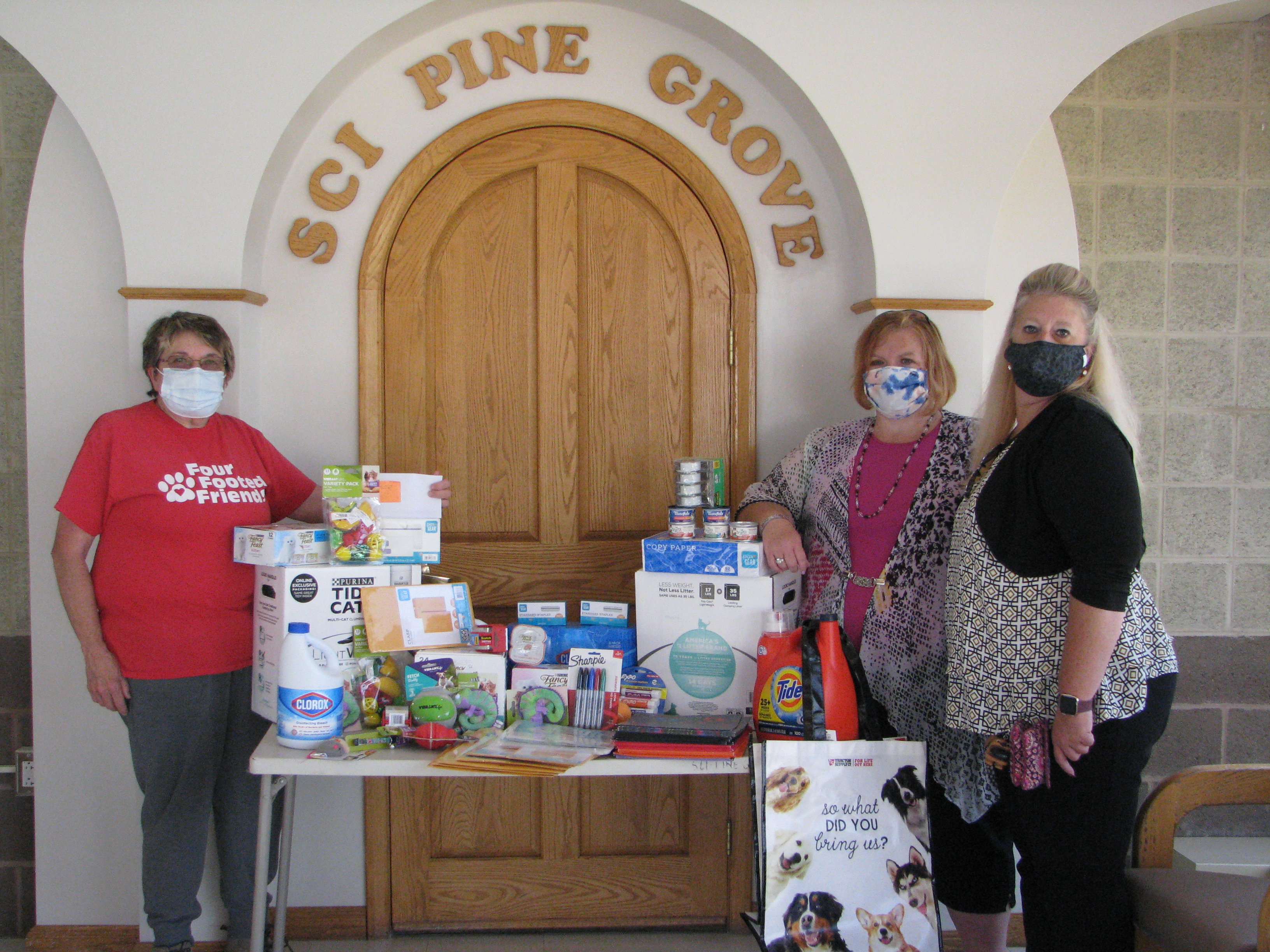 Three people stand by a table of donations