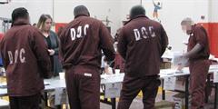 Four inmates look at information on tables at SCI Pine Grove's reentry fair