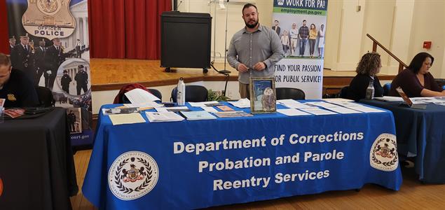 ​SCI Pine Grove Corrections Employment Vocational Coordinator Zach Ritchey standing at a table with information about the DOC at the Seton Hill Criminal Justice Day
