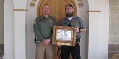 CO1 Matt Strittmatter stands with his supervisor while holding a framed certificate