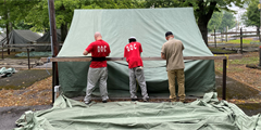 Three volunteers setting up tents at the fair.