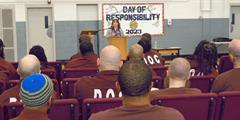 Inmates sit in the gym listening to a guest speaker at SCI Smithfield's Day of Responsibility