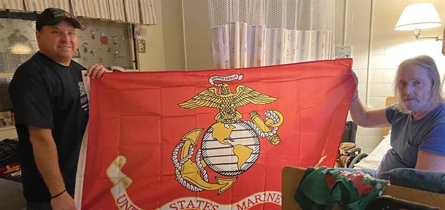 Two men holding the Marine Corps flag.