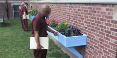 An inmate examines a new blue flowerbed box built by carpentry students