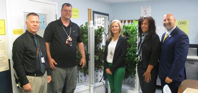 A group of people in front of a hydroponics planter