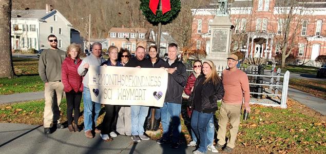 People hold a sign that says "#12MonthsOfKindness SCI Waymart"
