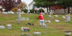 An inmate mows the lawn at a cemetery