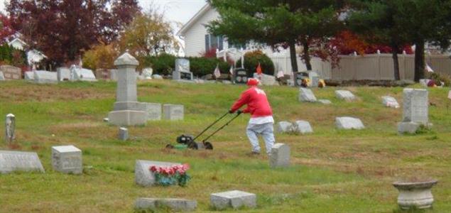 An inmate mows the lawn at a cemetery