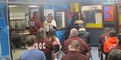 An incarcerated individual receives a certificate from an educator as other students watch at SCI Waymart.