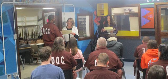 An incarcerated individual receives a certificate from an educator as other students watch at SCI Waymart.