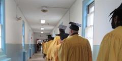 Incarcerated individuals in caps and gowns walk in their processional at SCI Waymart's graduation ceremony