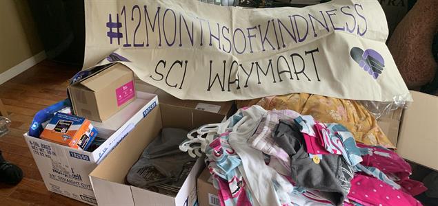 Boxes of donated items with a sign that says "#12MonthsOfKindness SCI Waymart"