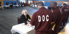 Two incarcerated individuals speak to an attendee at the SCI Waymart Reentry Fair.
