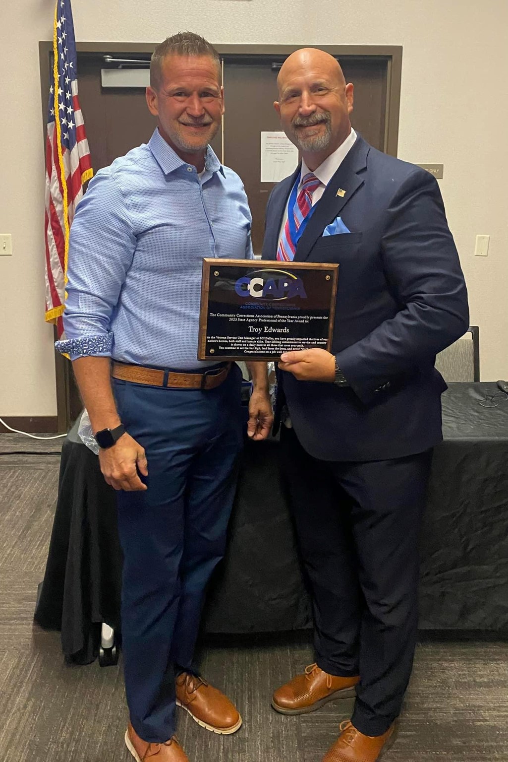 SCI Dallas VSU Unit Manager Troy Edwards receives a plaque from Bureau of Reentry Coordination Director Daniel McIntyre.