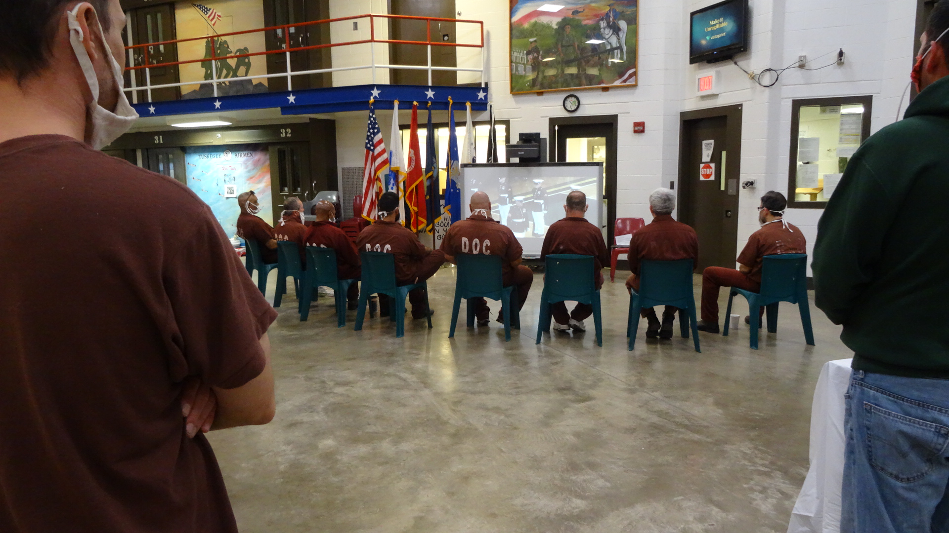 Inmates watch military drill on a projector