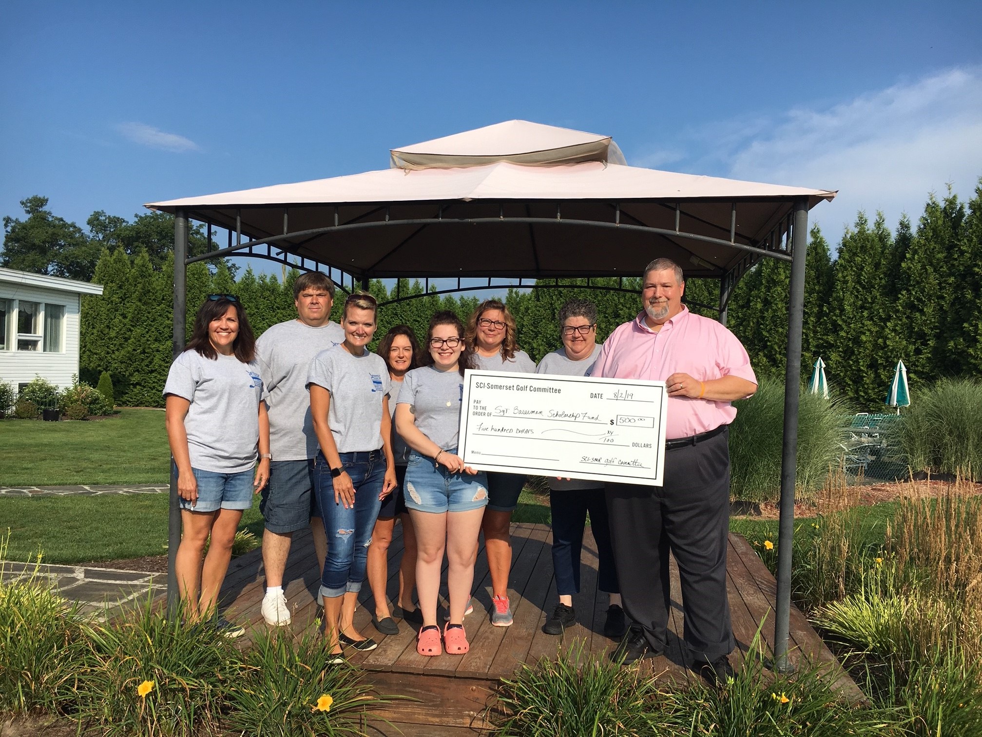 Staff hold a check at the Baserman Memorial Golf Tournament fundraiser