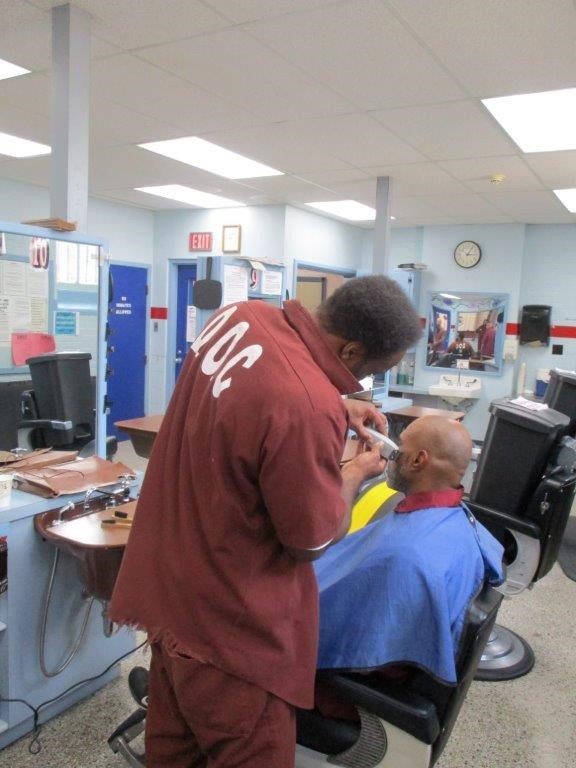 A barber cuts an inmate's hair