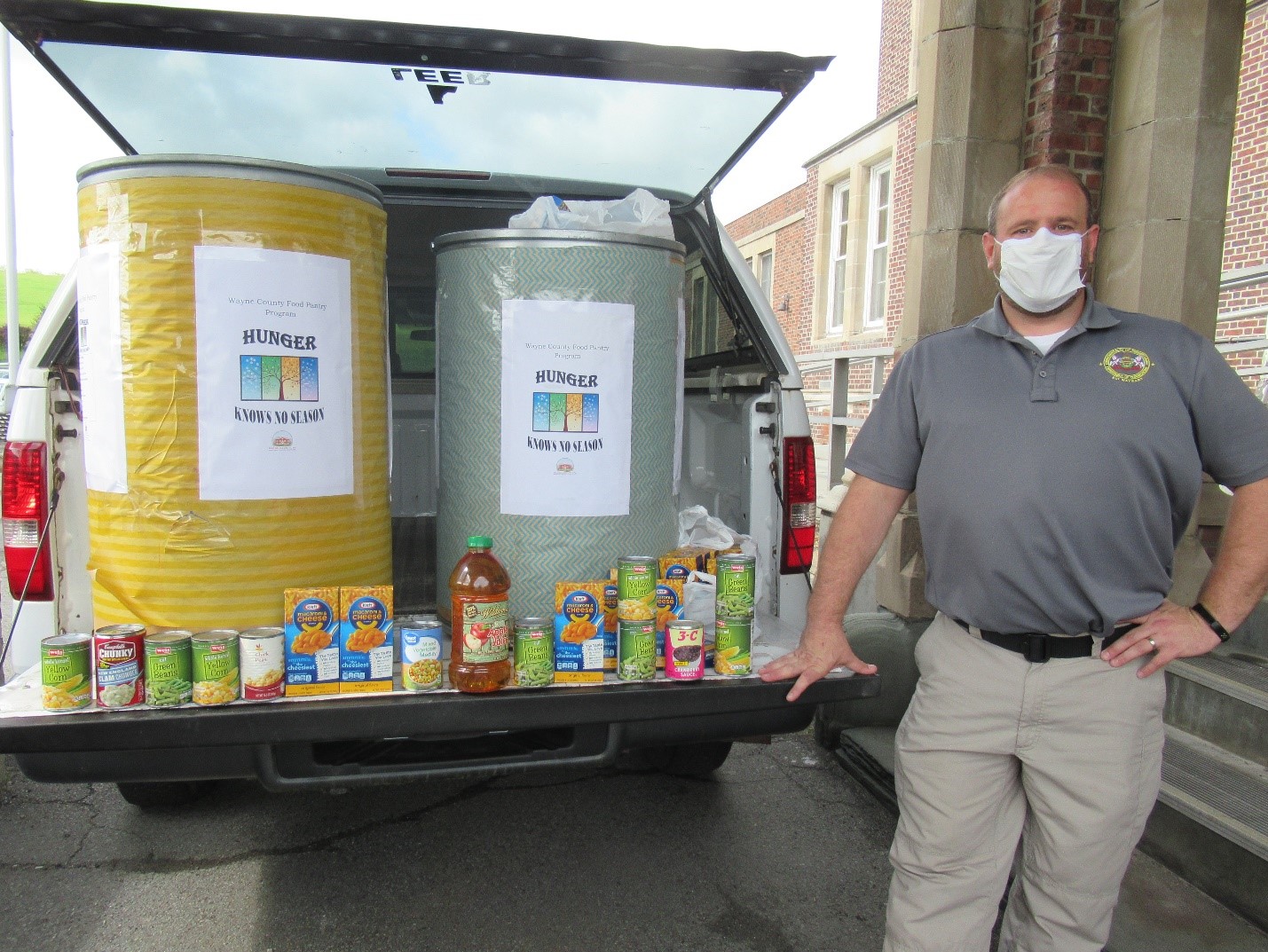 An employee stands with food pantry donations