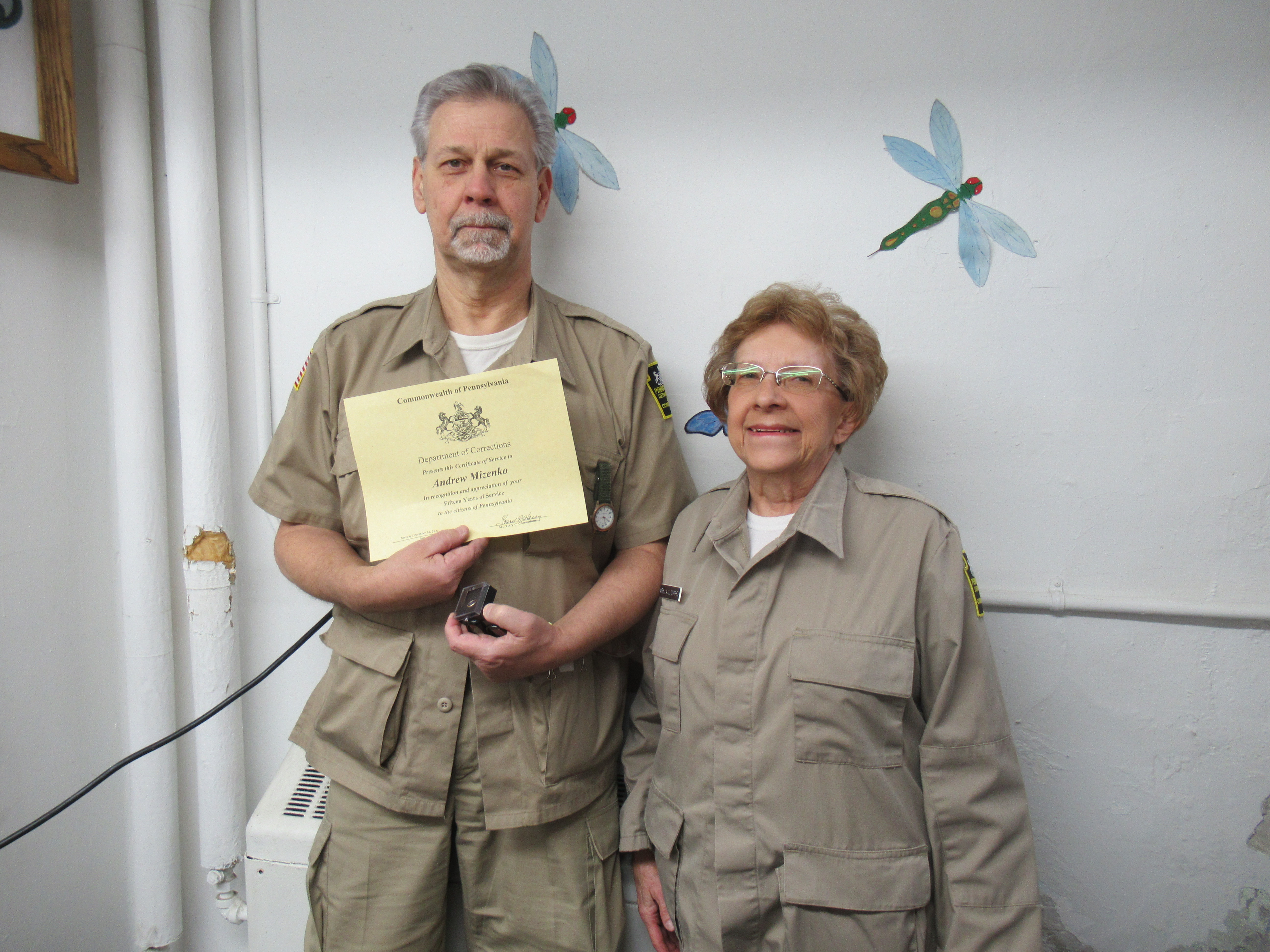 Garment Factory Foreman ​Andrew Mizenko​ holds a certificate while standing with his supervisor