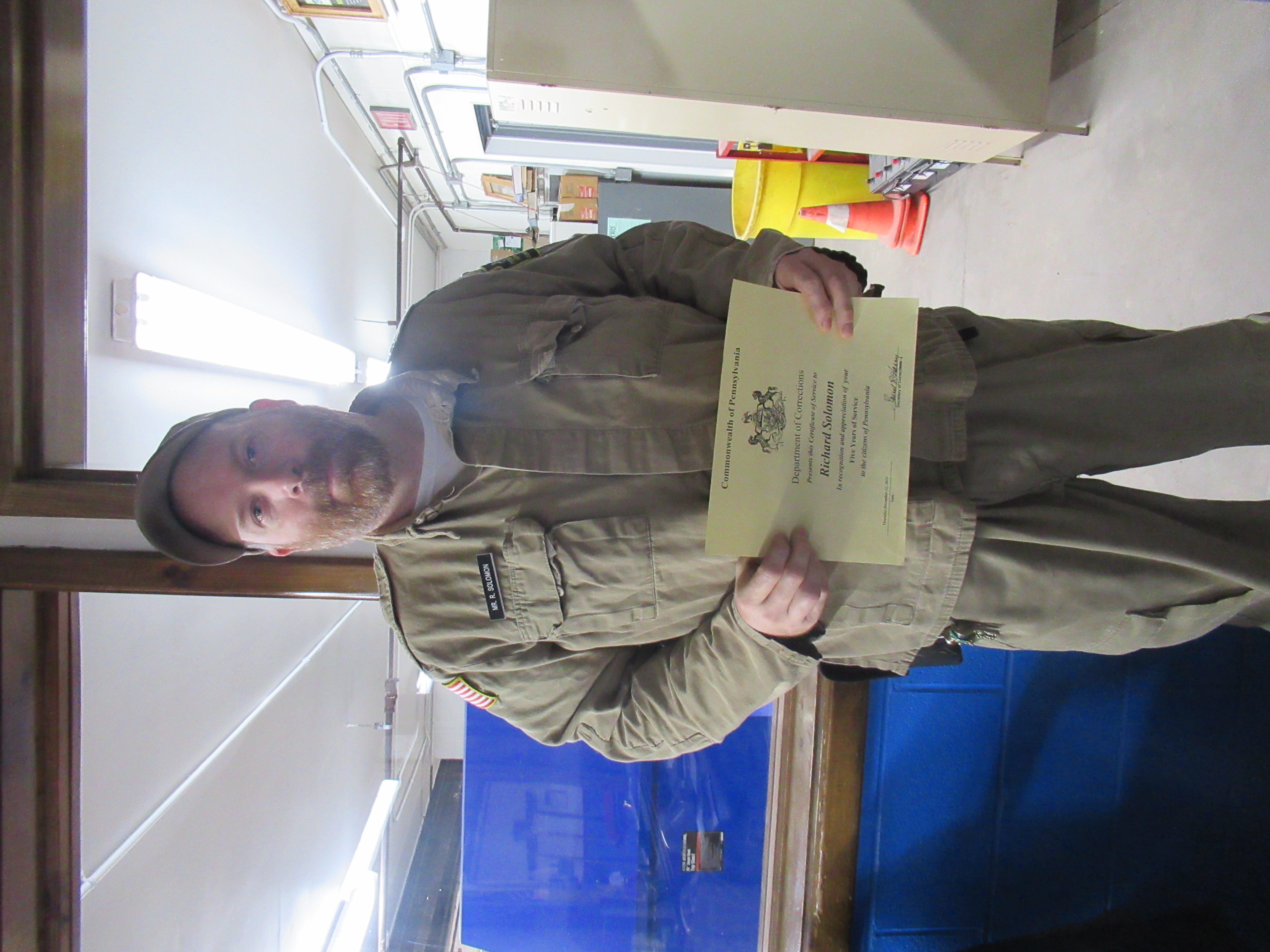 Corrections Automotive Mechanic Trades Instructor Richard Solomon holding a certificate.